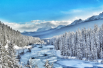 Snow-covered trees and mountains surround the icy Bow River in Banff