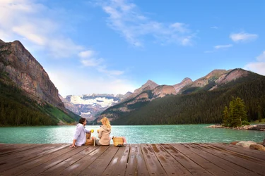 A couple enjoys a picnic on the dock over Lake Louise