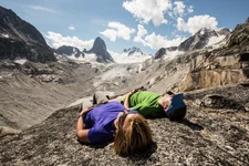 Two hikers lying on a mountainside