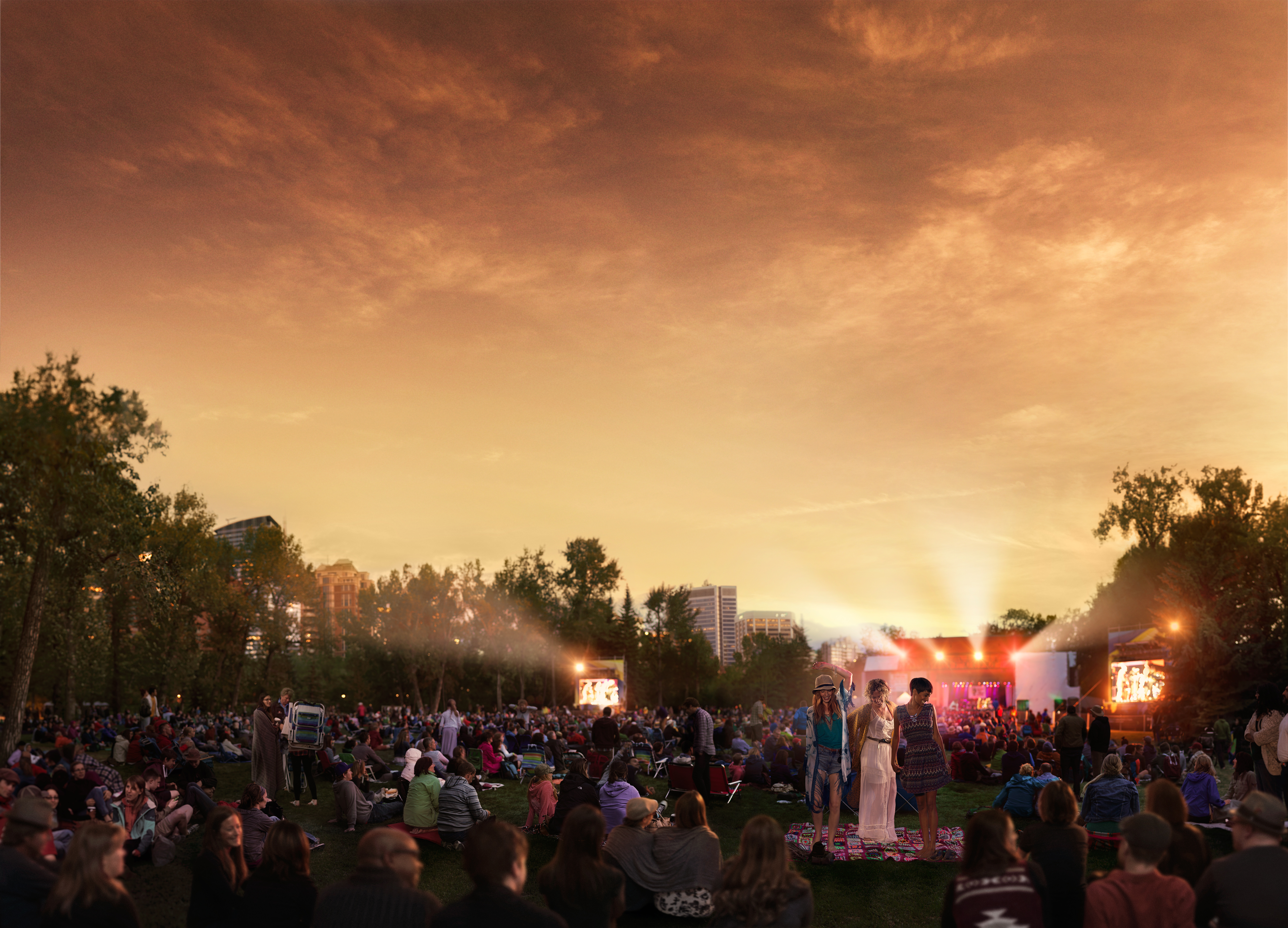 People enjoy music live from illuminated stage at the Calgary Folk Festival during sunset in Calgary