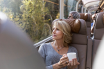 A woman sits in glass-domed train car with a warm drink