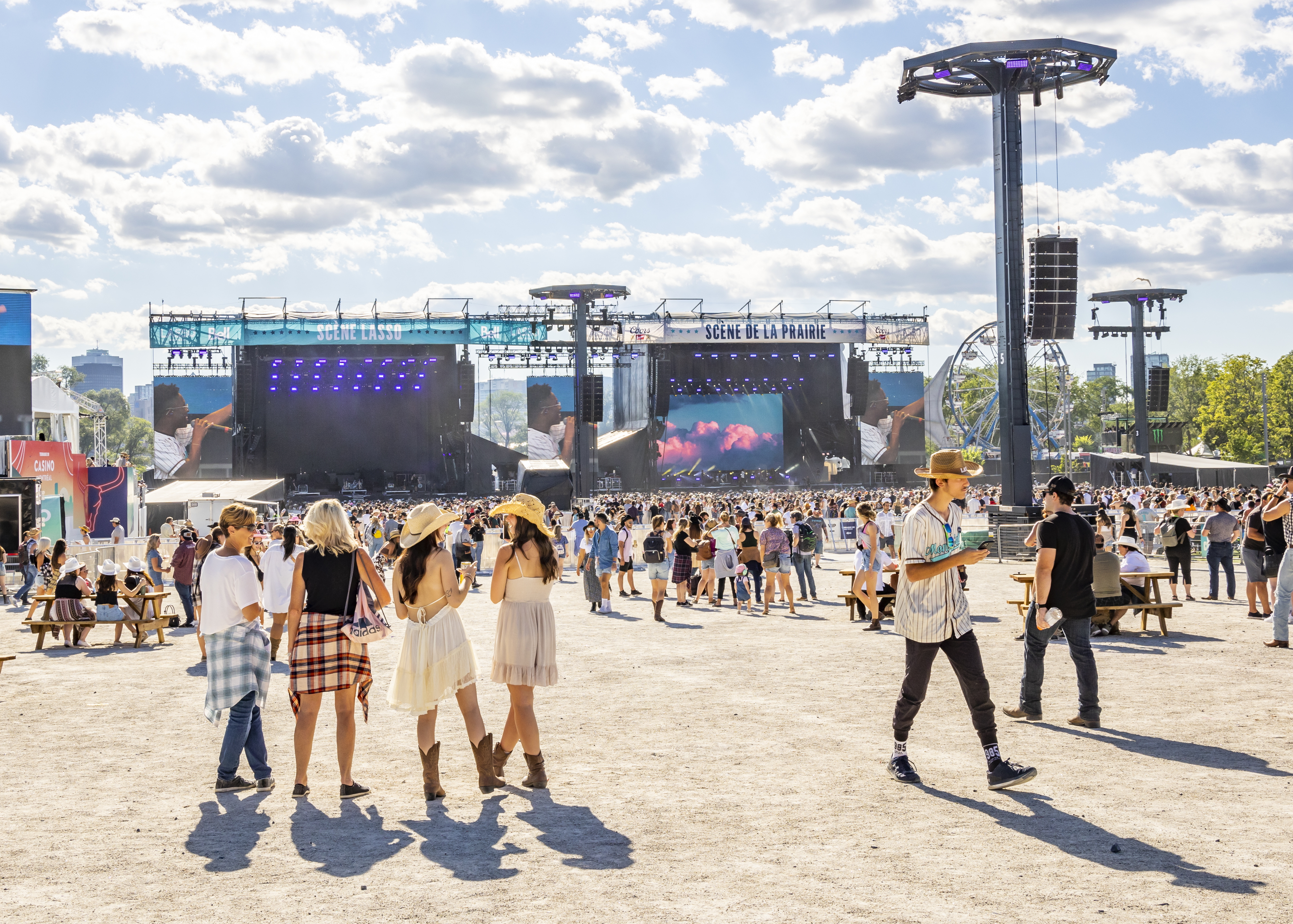 People dressed in summer outfits and cowboy hats at an outdoor country music festival