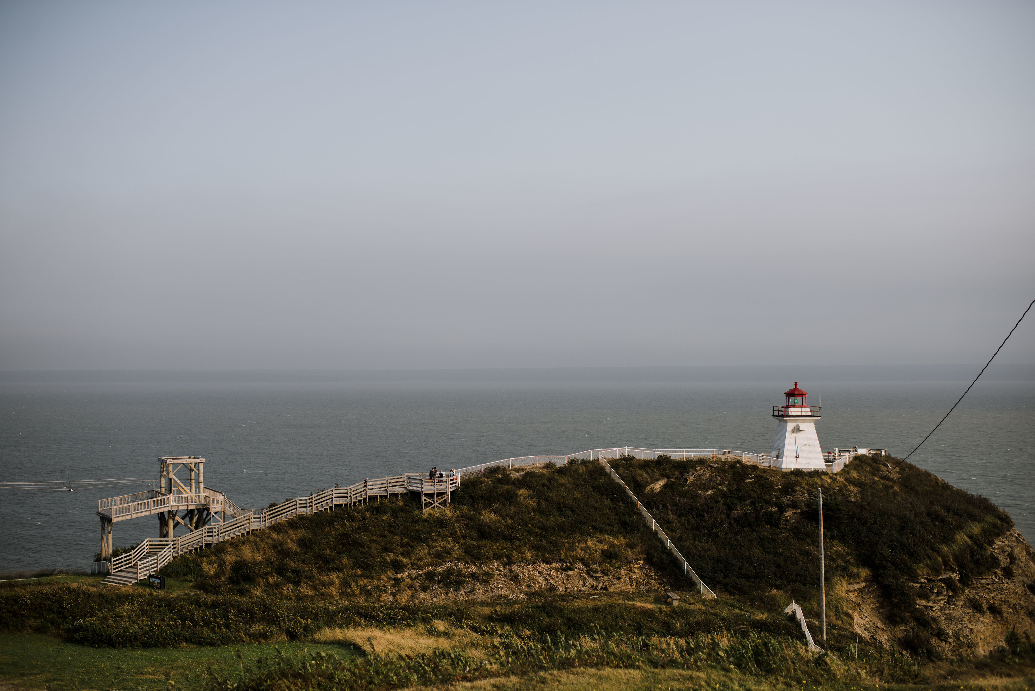 Lighthouse on mossy green cliff overlooking inlet