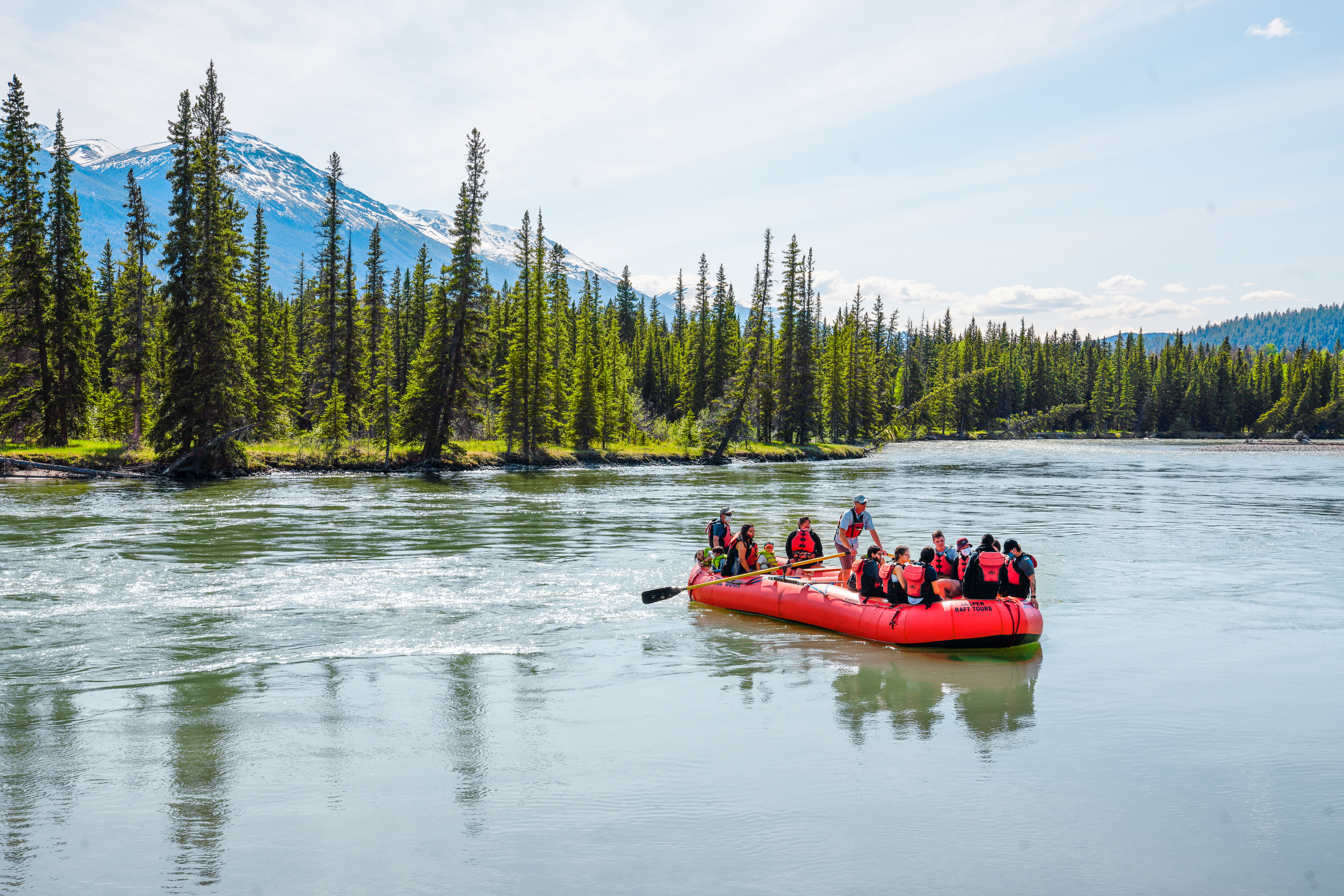 A group with a guide on a large red raft on the Athabasca River