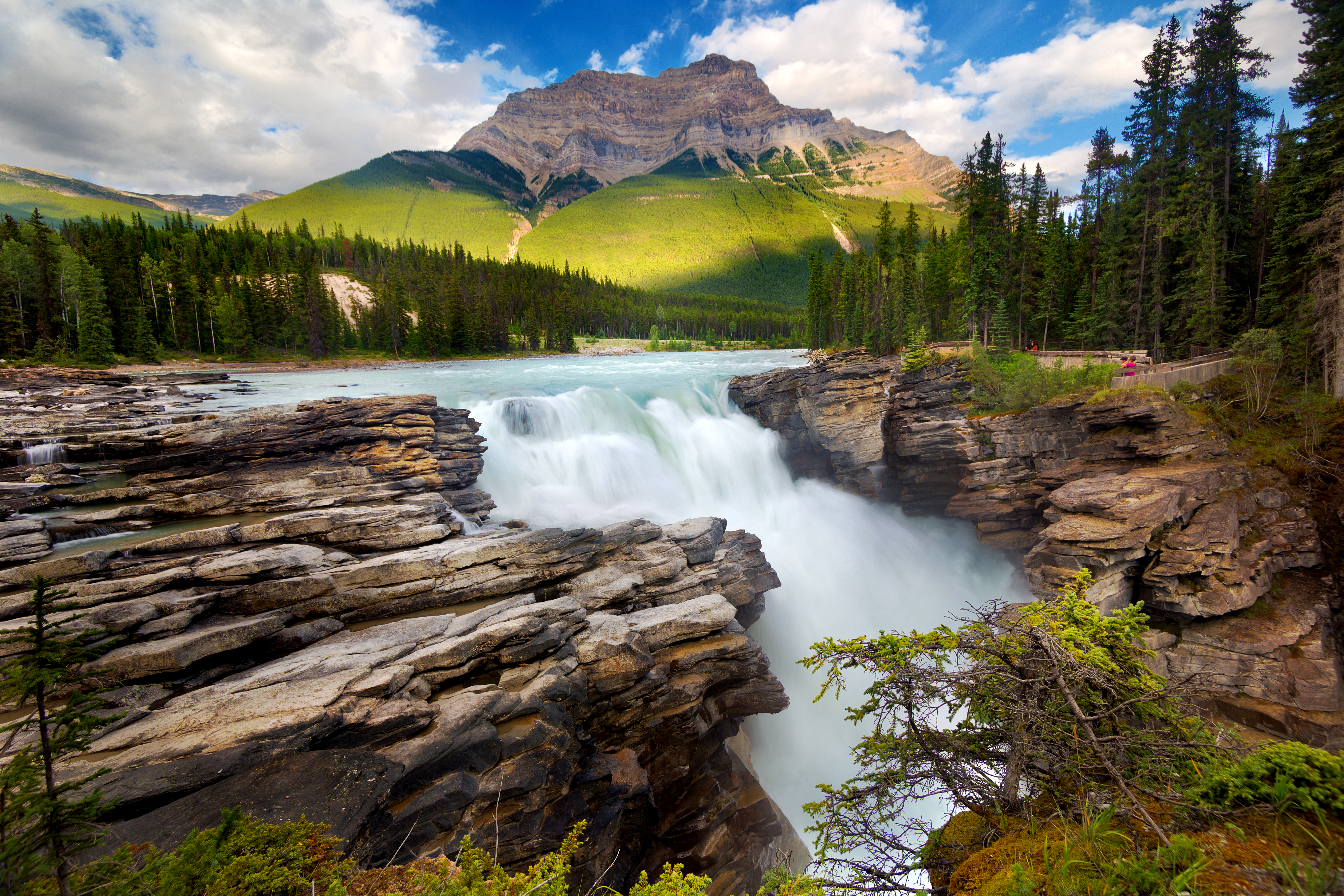 Rocky ledge and waterfall with mountains in the background