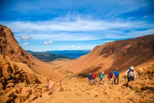 A group of hikers make their way through the orange-hued Tablelands in Gros Morne National Park.