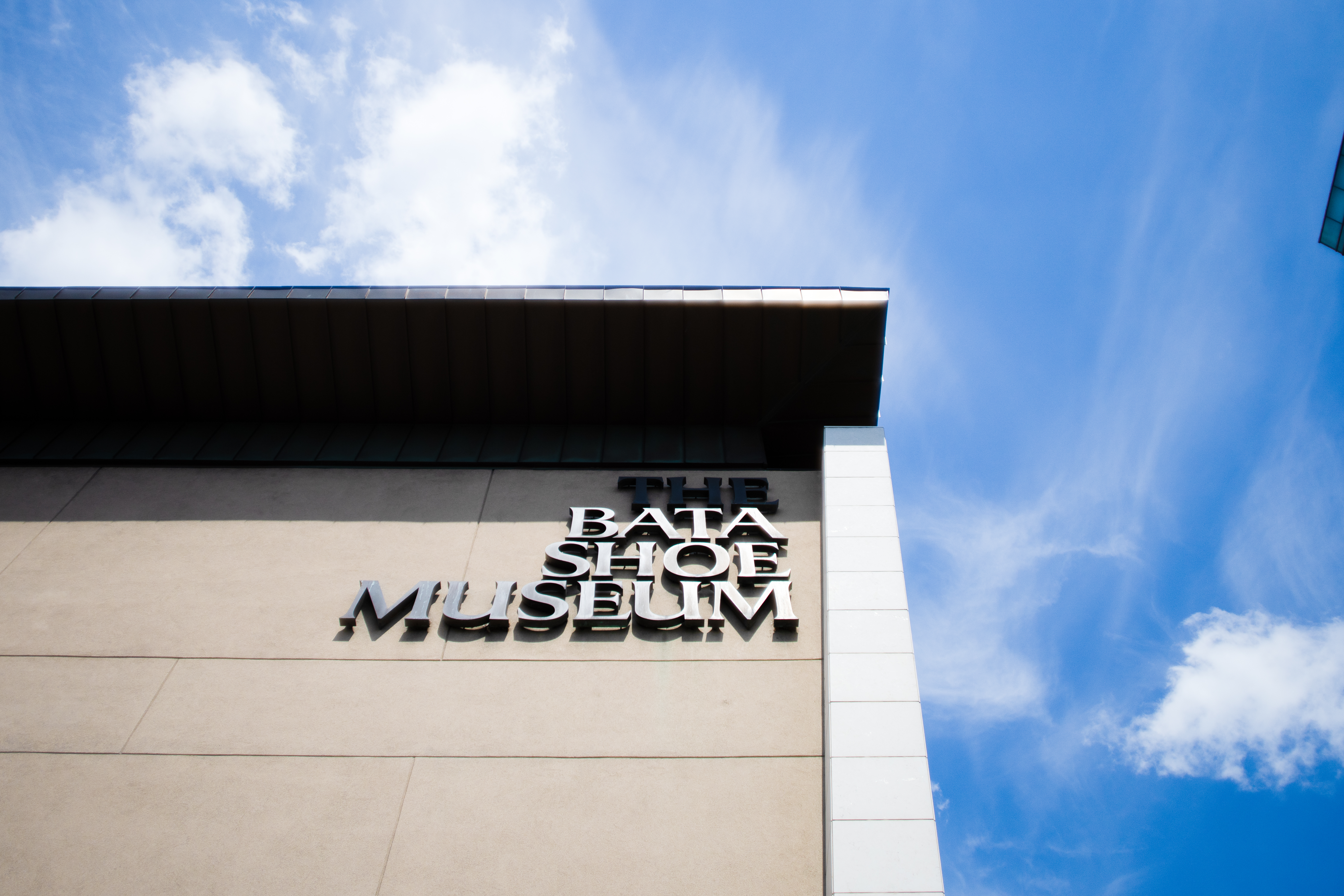 The Bata Shoe Museum signage on the museum building corner against a blue sky