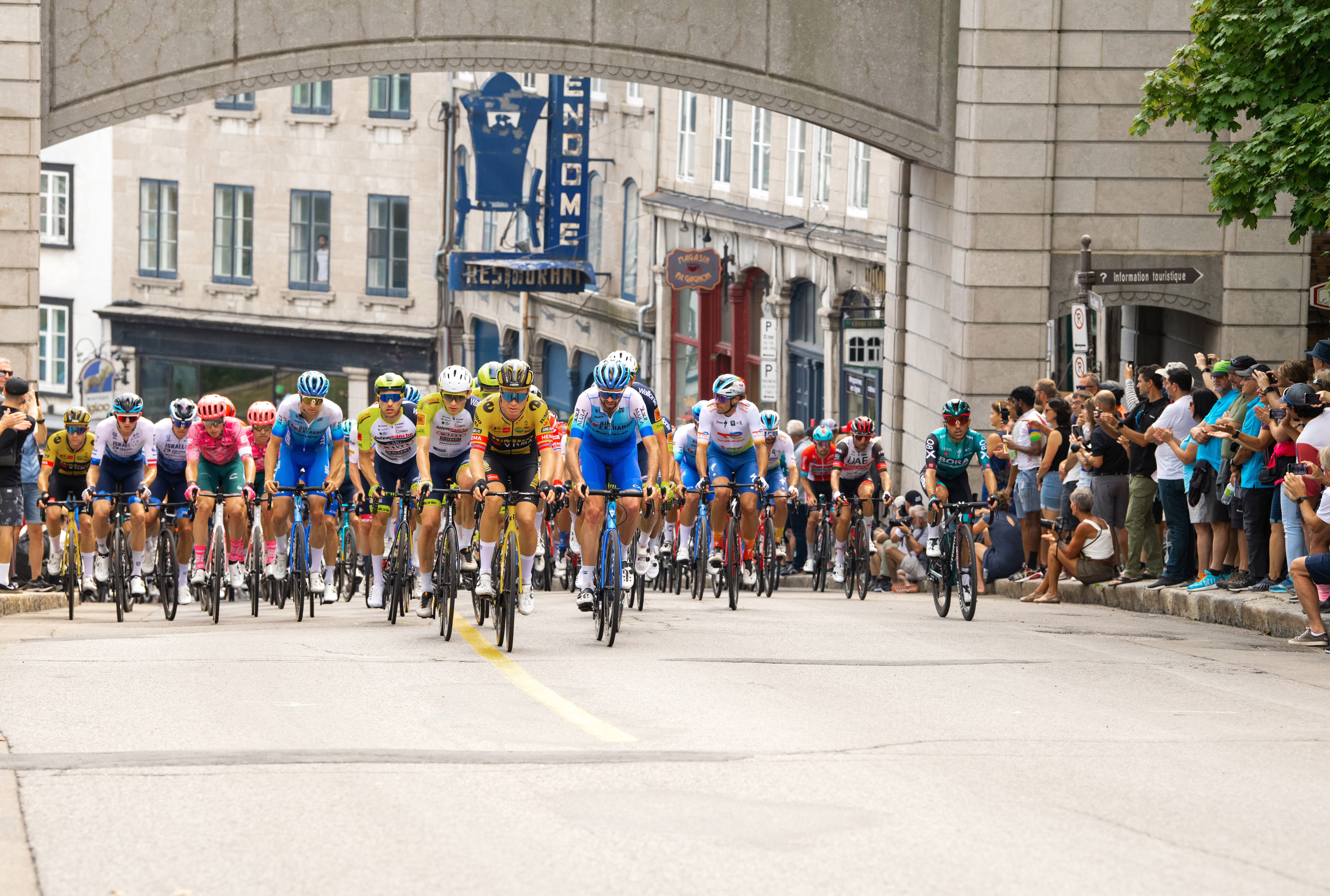 A large group of cyclists racing through Quebec City as a crowd watches