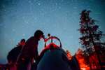 A person looks up at the starry sky using a large telescope in Jasper National Park