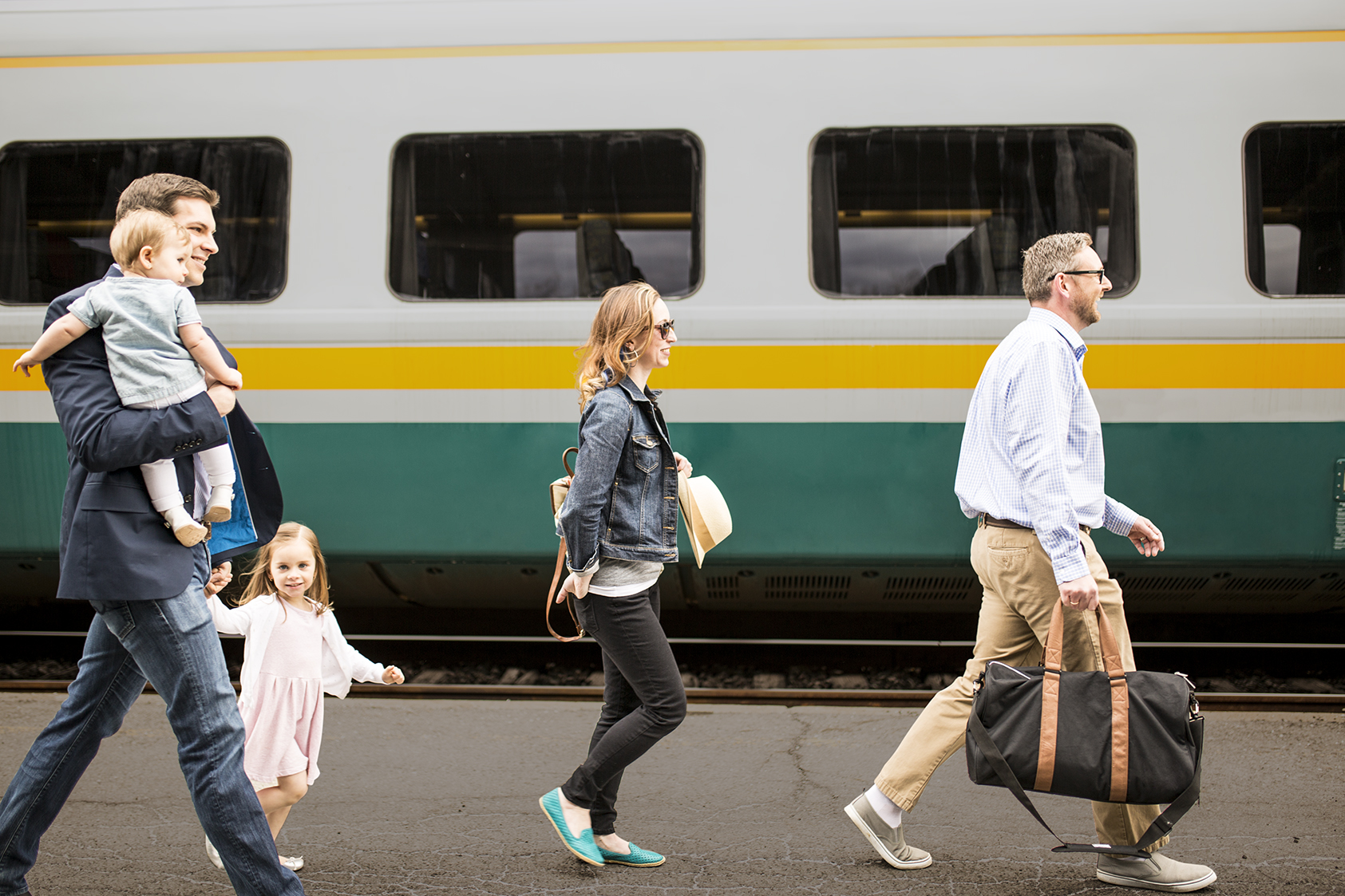 A family walk along the platform next to a VIA Rail train
