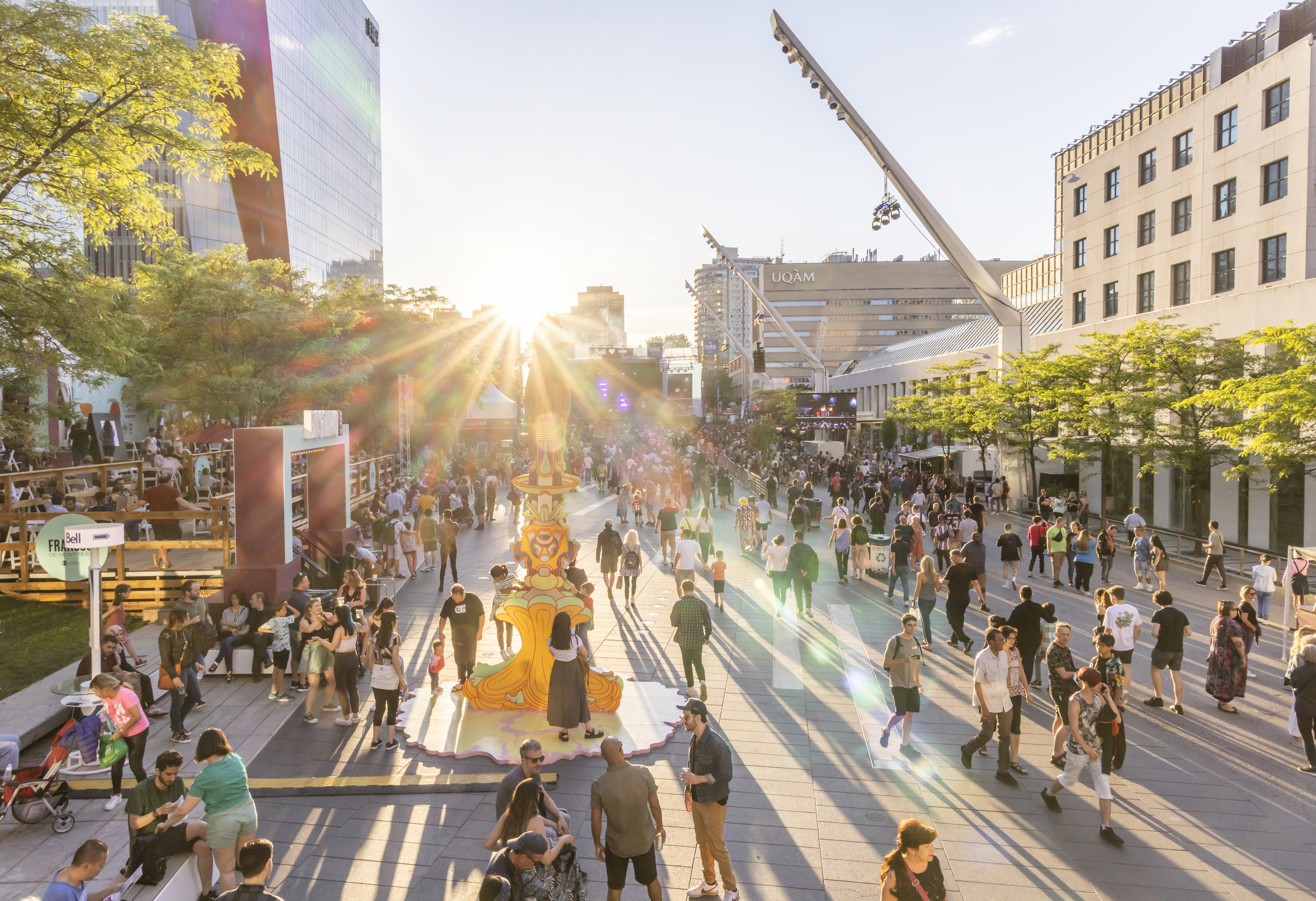 Sun shines over groups of people walking through Montreal's cultural district during a festival