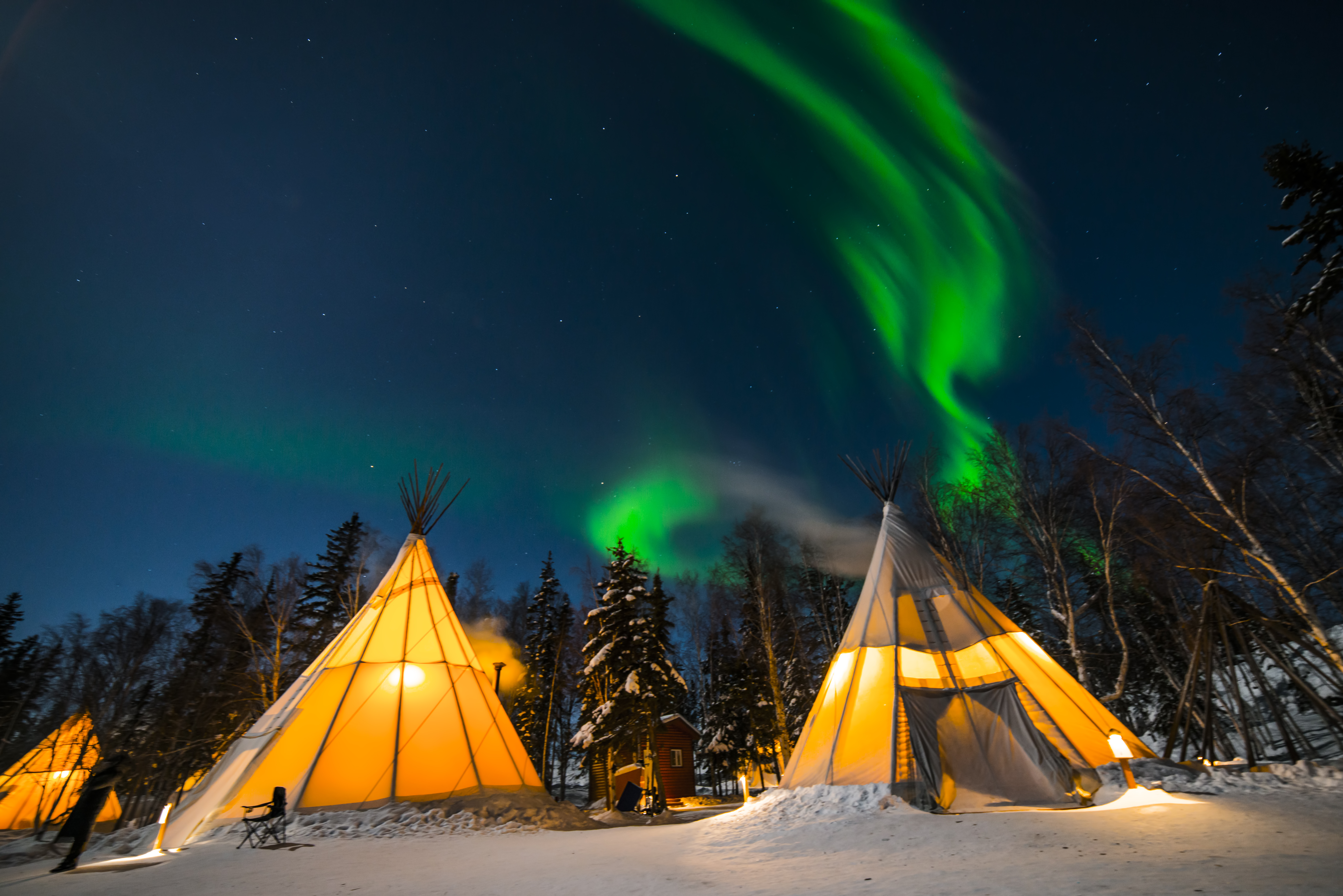 Deep blue sky and green Northern Lights above Aurora Village teepees near downtown the Northwest Territories' Yellowknife in Canada 