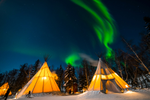 Deep blue sky and green Northern Lights above Aurora Village teepees near downtown the Northwest Territories' Yellowknife in Canada 
