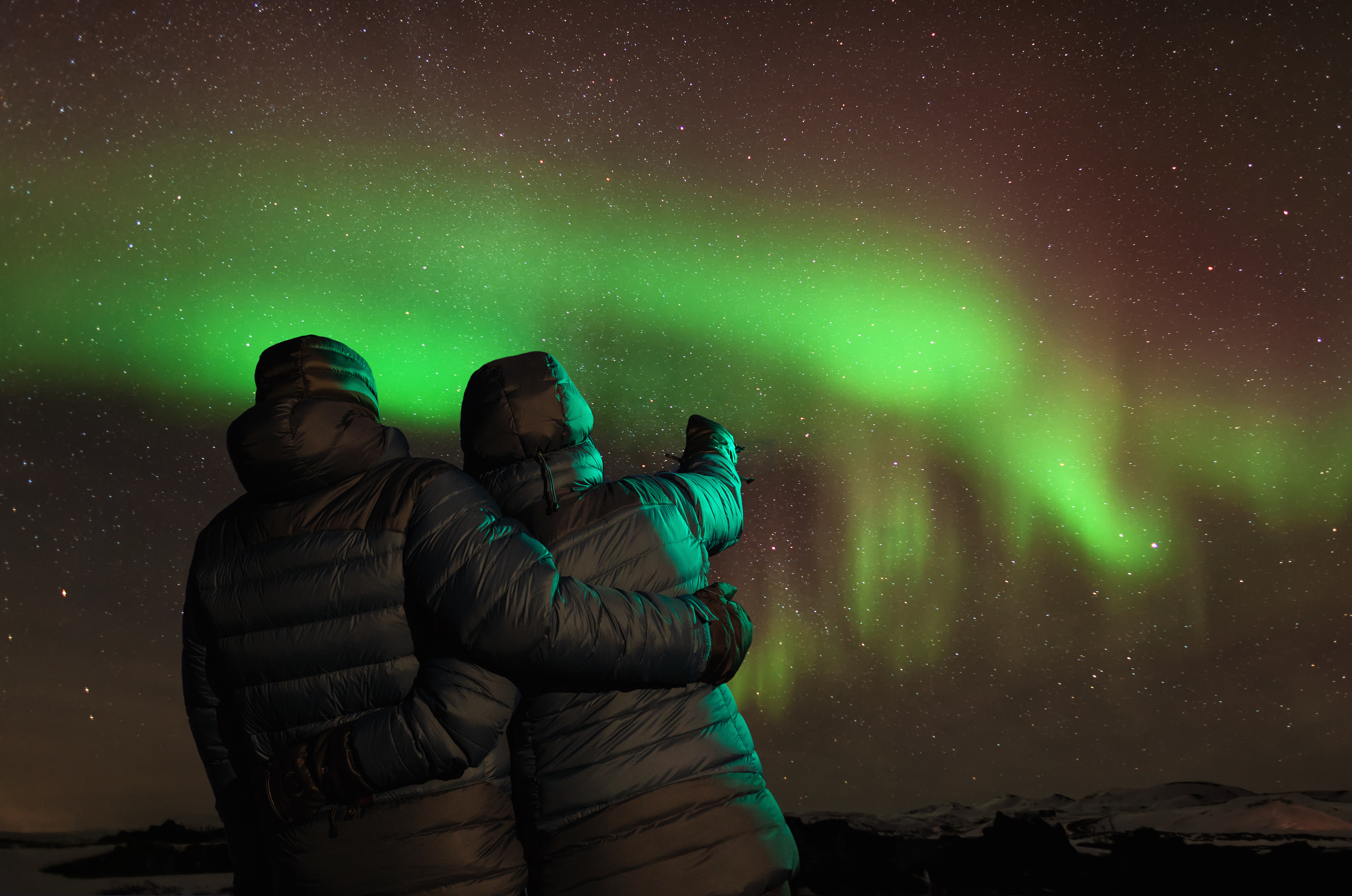 Couple embrace while experiencing northern lights