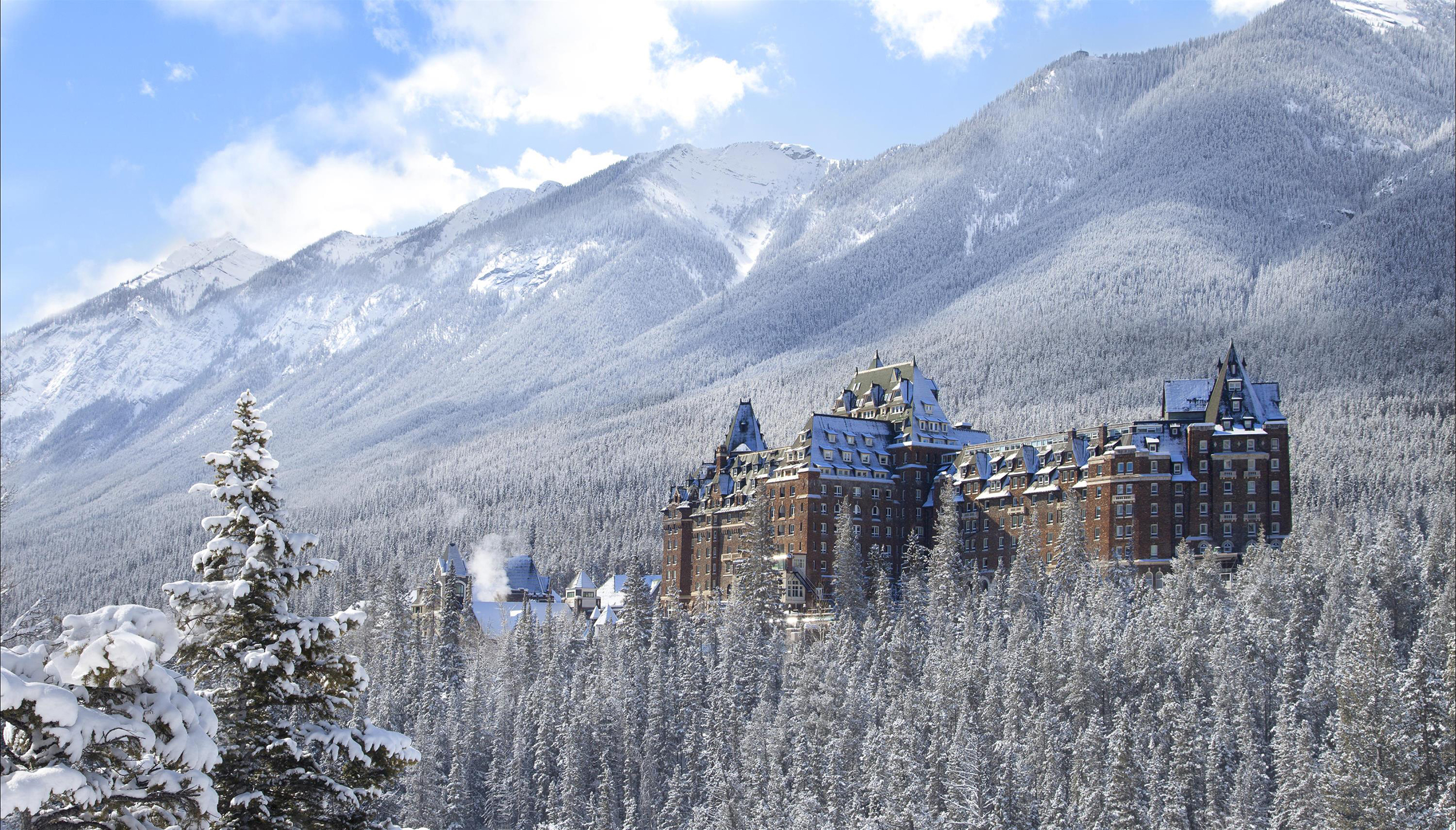 Snowy mountains and trees with Fairmont Banff Springs hotel in the middle