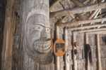 Close up of an indigenous wood carving and other artifacts hanging in a wooden lodge