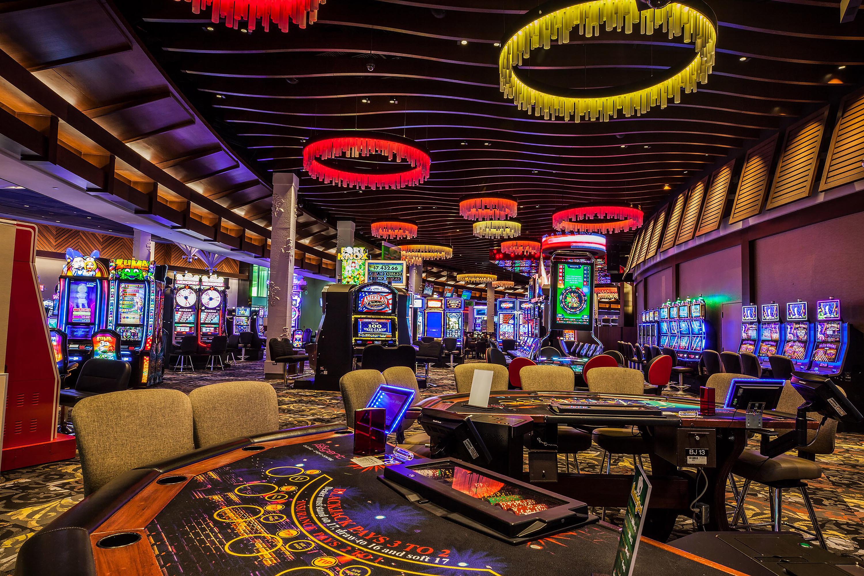 Interior of a casino with bright lights, slot machines and gaming tables 