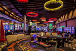 Interior of a casino with bright lights, slot machines and gaming tables 