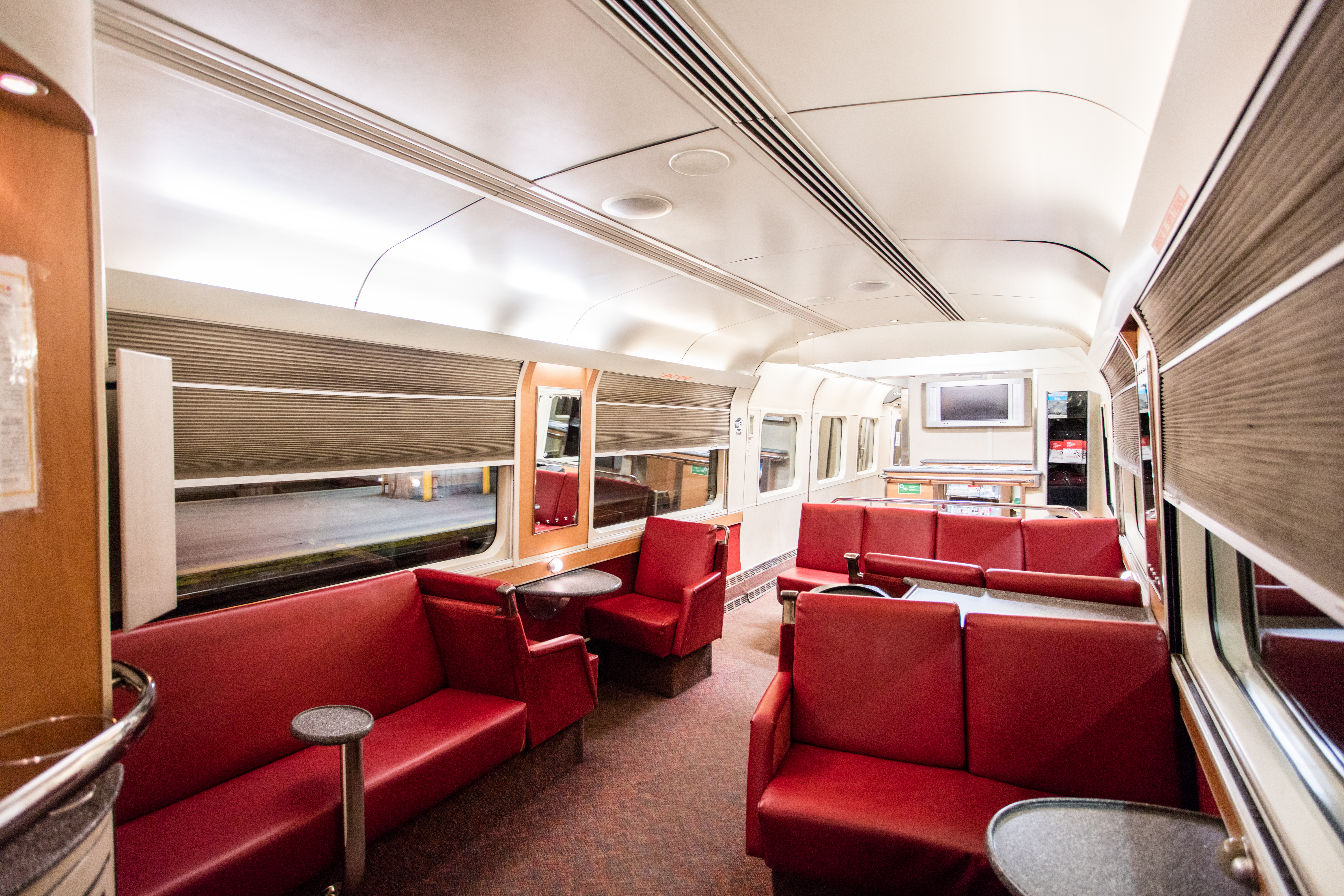 Red lounge chairs and tables in a service car onboard The Ocean train
