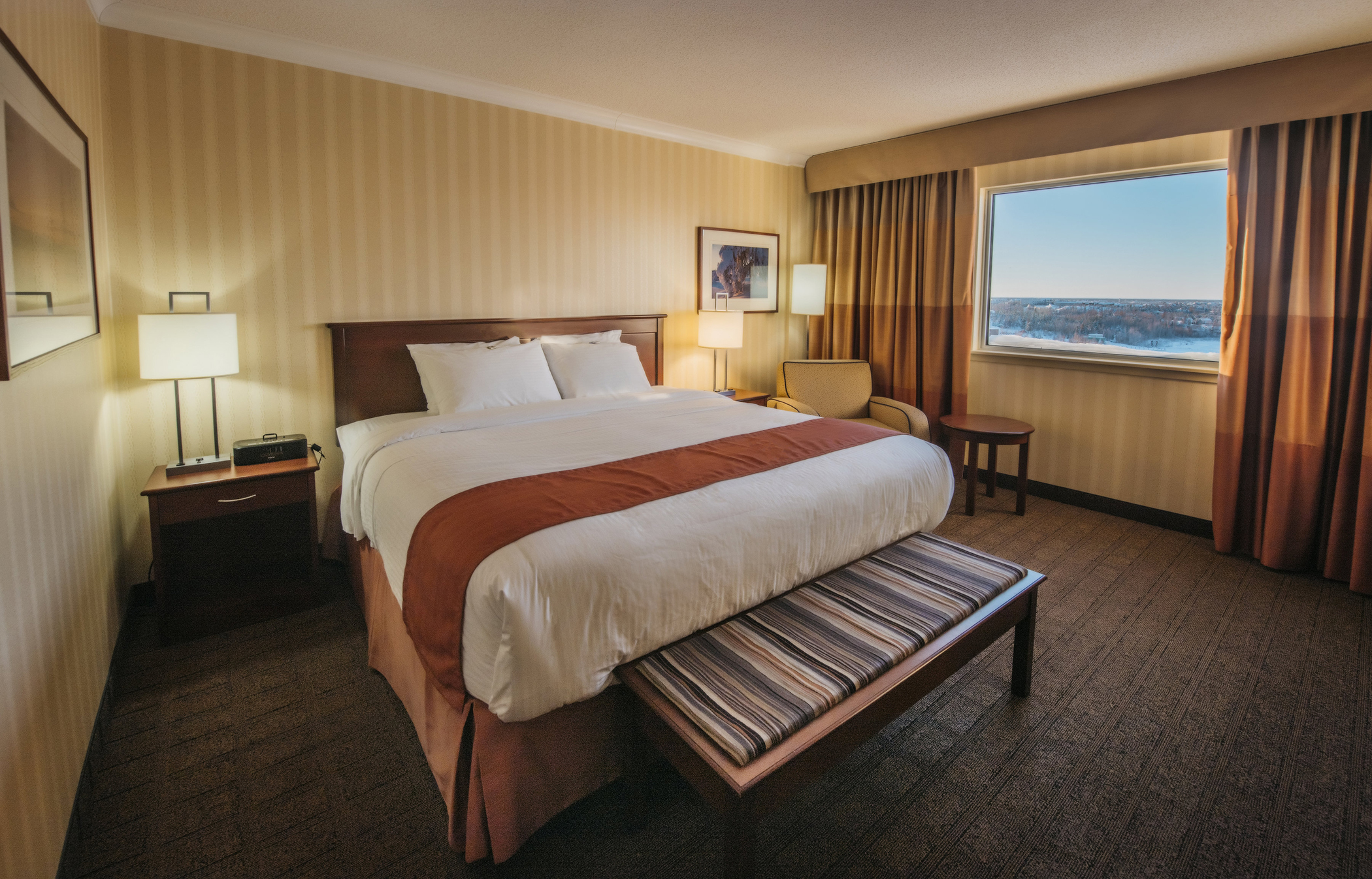 Hotel room with king-size bed and furniture with view in Superior Room at the Explorer Hotel located downtown in Northwest Territories’ Yellowknife 