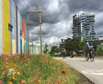 people cycle past colourful mural on Arbutus Greenway
