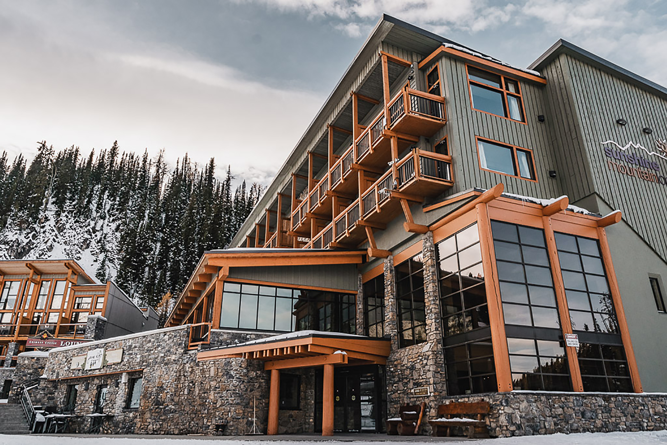 Exterior view of Sunshine Mountain Lodge next to snow-covered trees