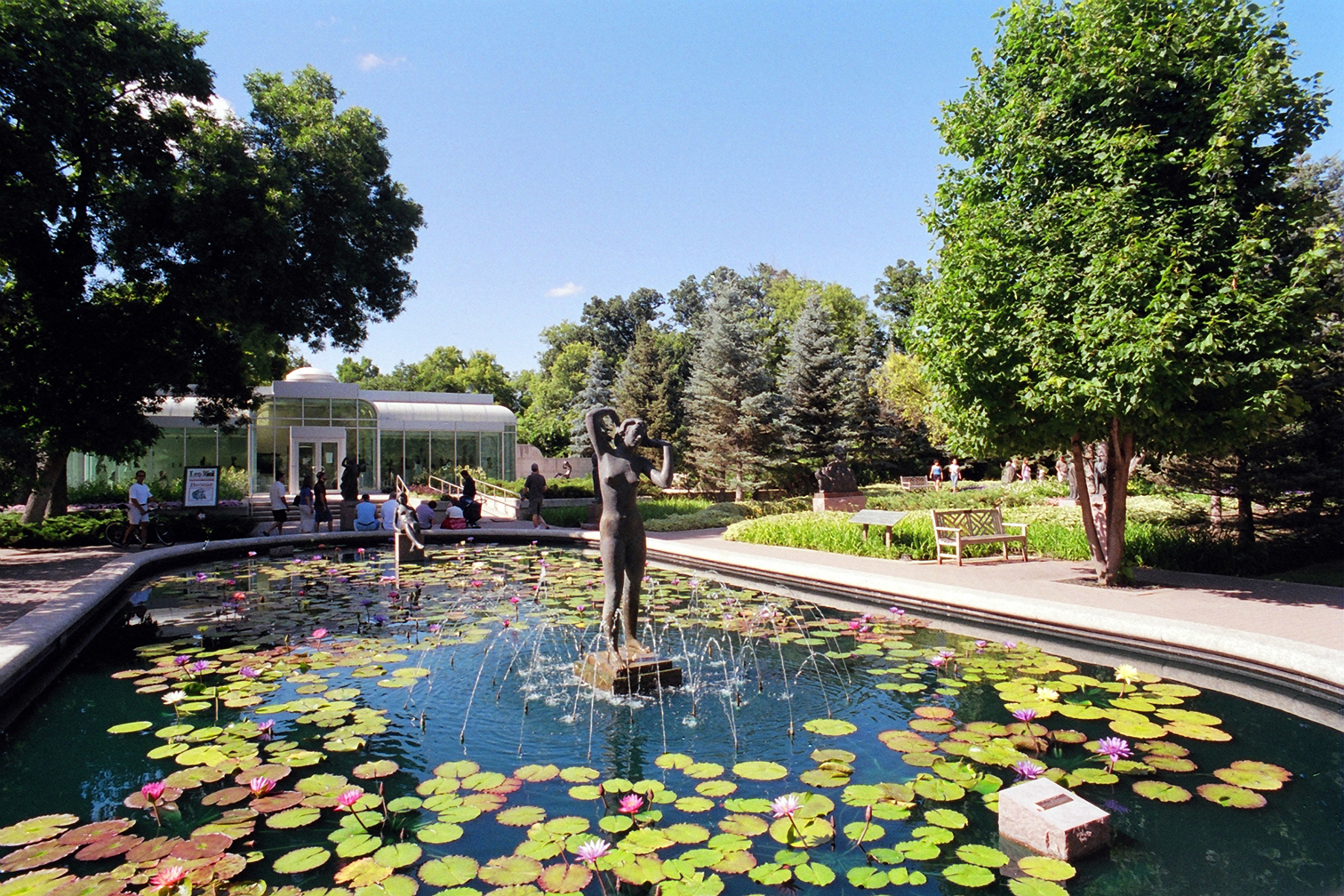 A pond and water statue in a Sculpture Garden on a sunny day