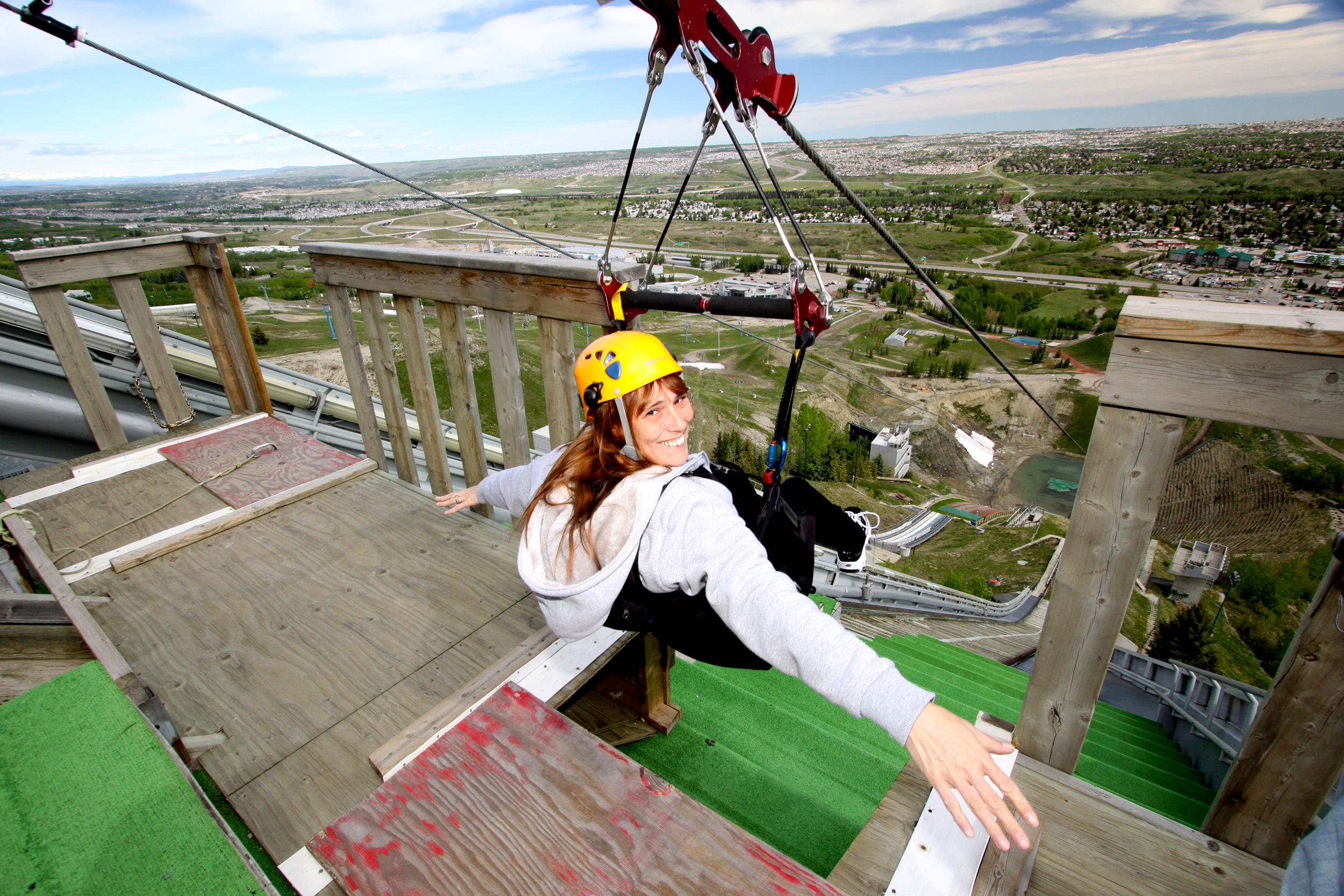A woman smiling at the camera just before she goes on the zipline at Canada Olympic Park