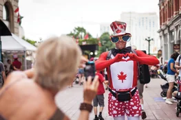 A photo being taken of someone on the street dressed in festive Canada Day clothing and accessories