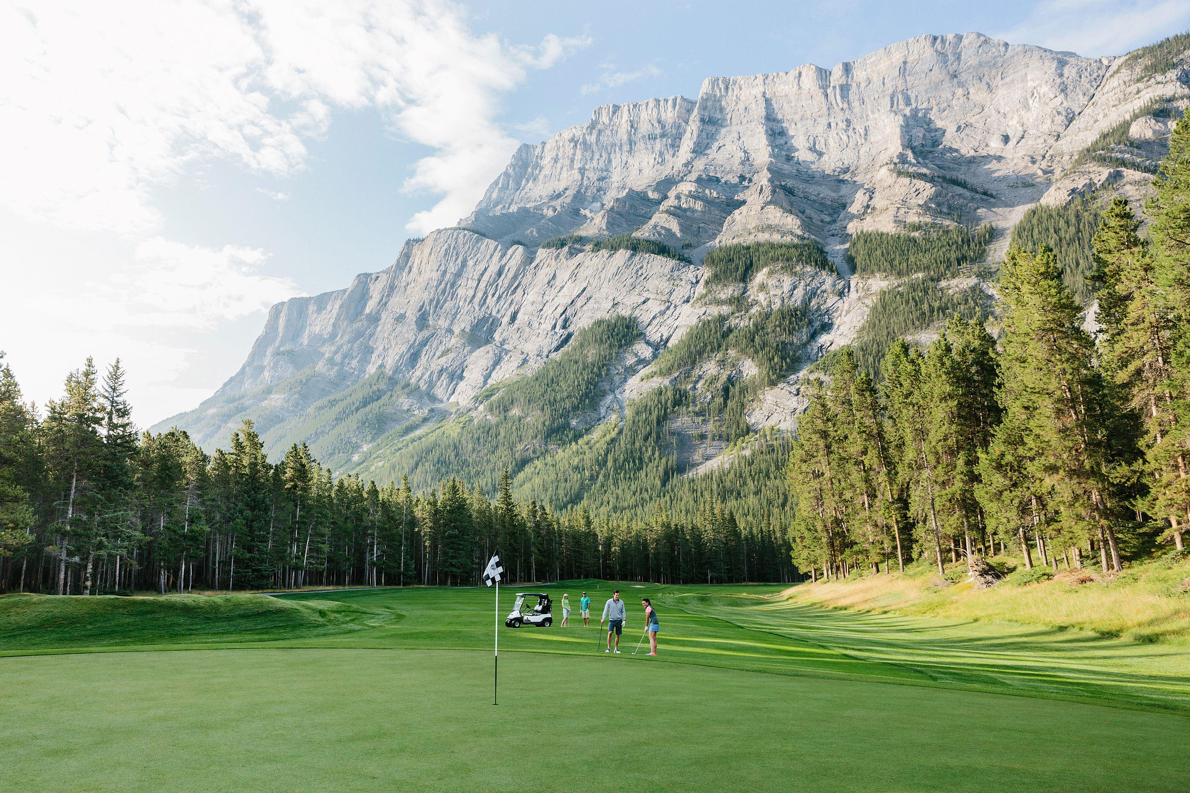 The view from the 5th hole, with golfers and mountains in the distance at Fairmont Banff Springs Golf Course.