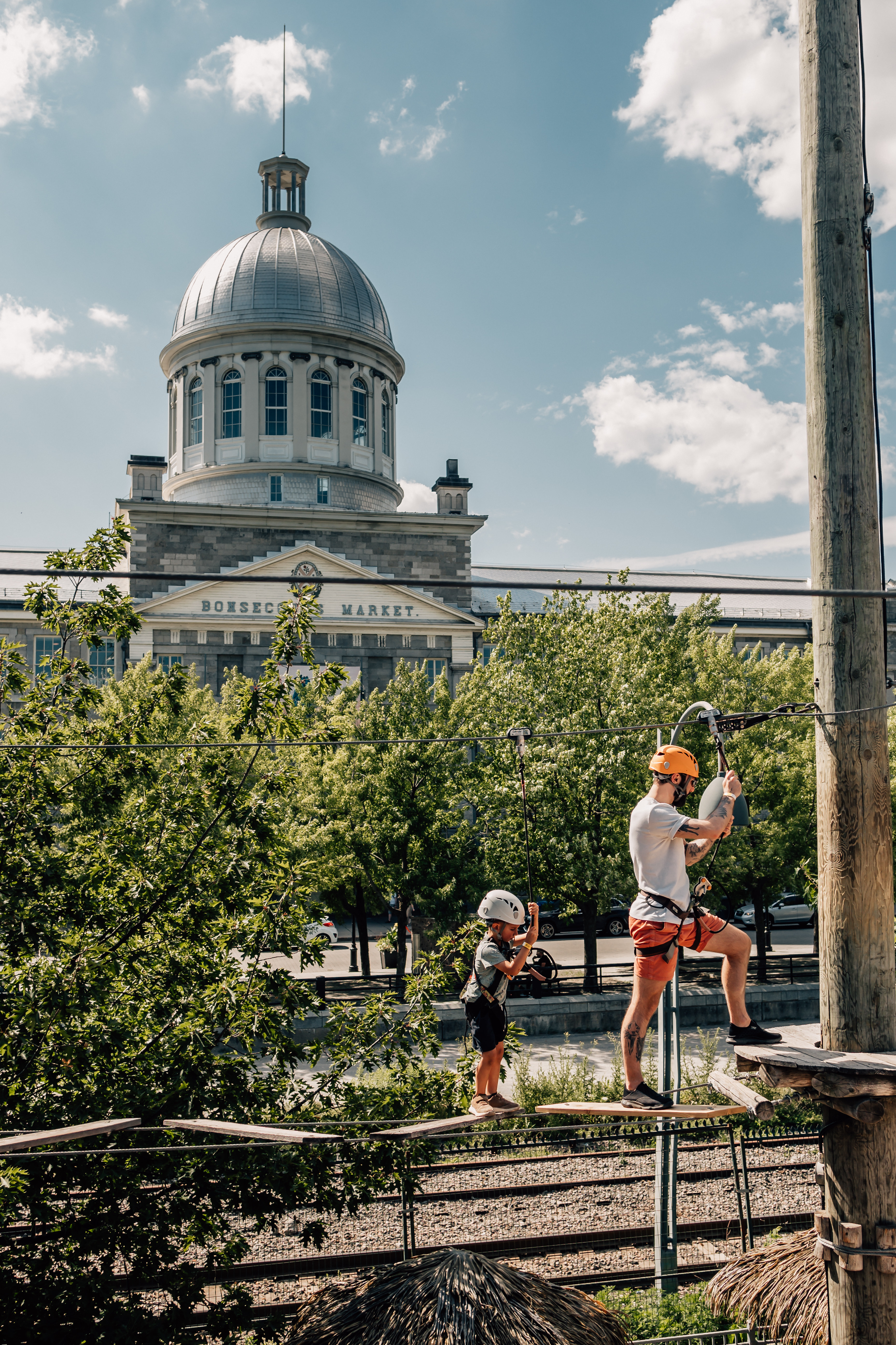 A man and young child walk along a rope bridge on a zipline course in Montreal