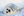 A harp seal with a grey coat lies in white snow