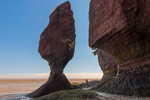 Woman photographs Bay Fundy's massive sandstone formation in Hopewell Rocks by the sea