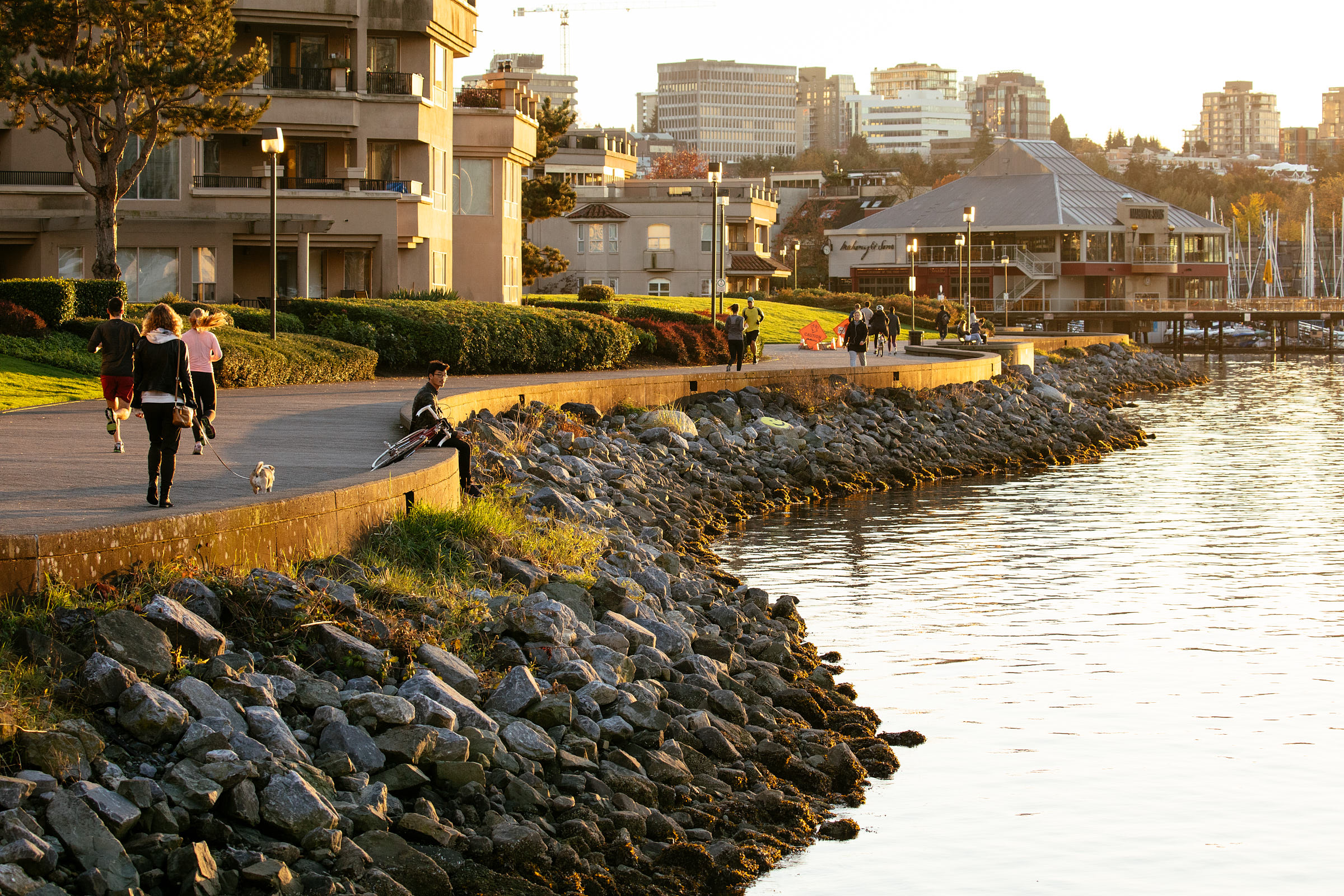 People walking along the False Creek seawall as the sun sets 