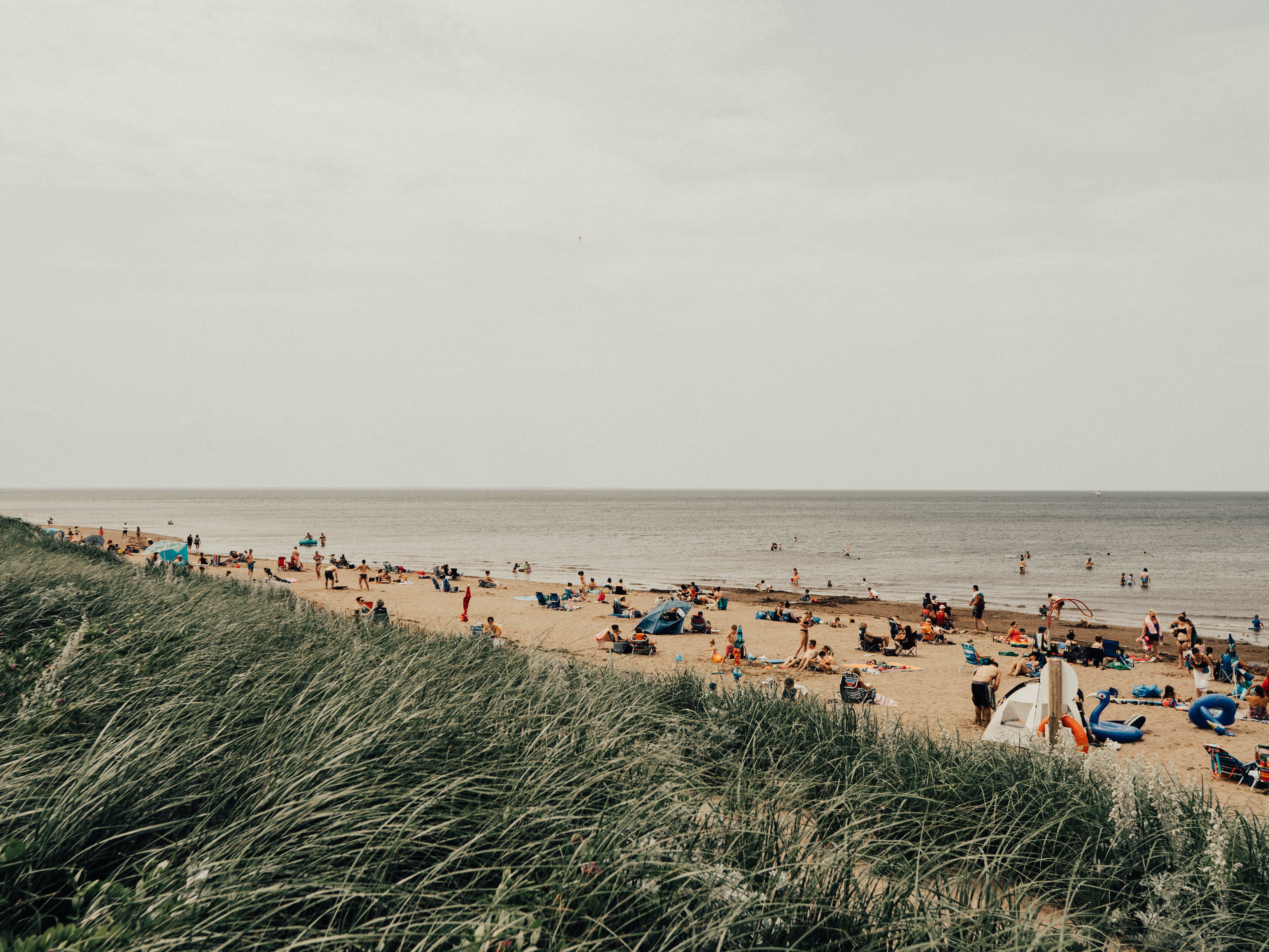 Visitors relax on Aboiteau Beach’s coastal sandy shore and enjoy the water