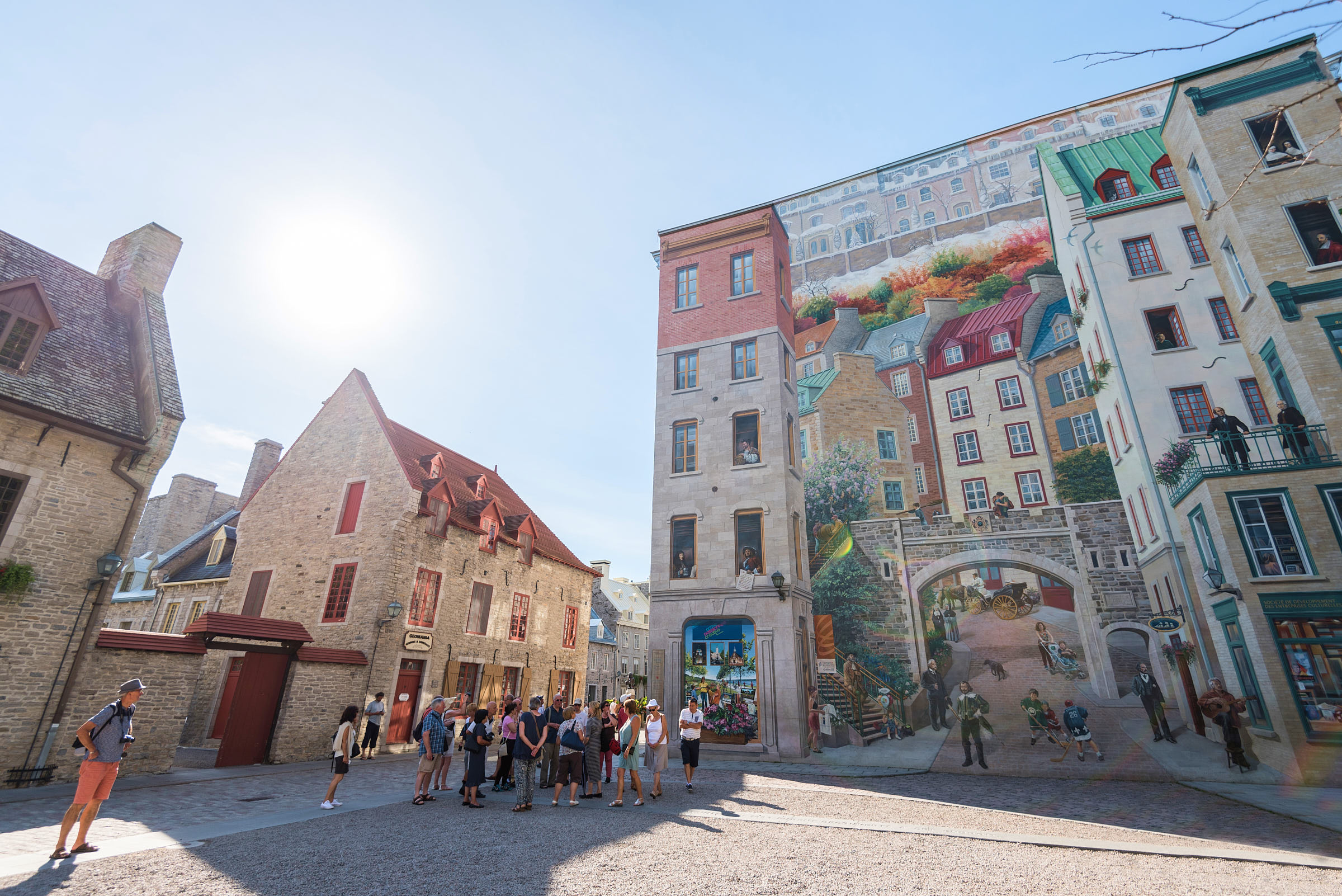 A small group of people in front of a large mural in Old Quebec