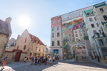 A crowd of tourists gather by five storey building with a mural in a neighbourhood in Quebec City