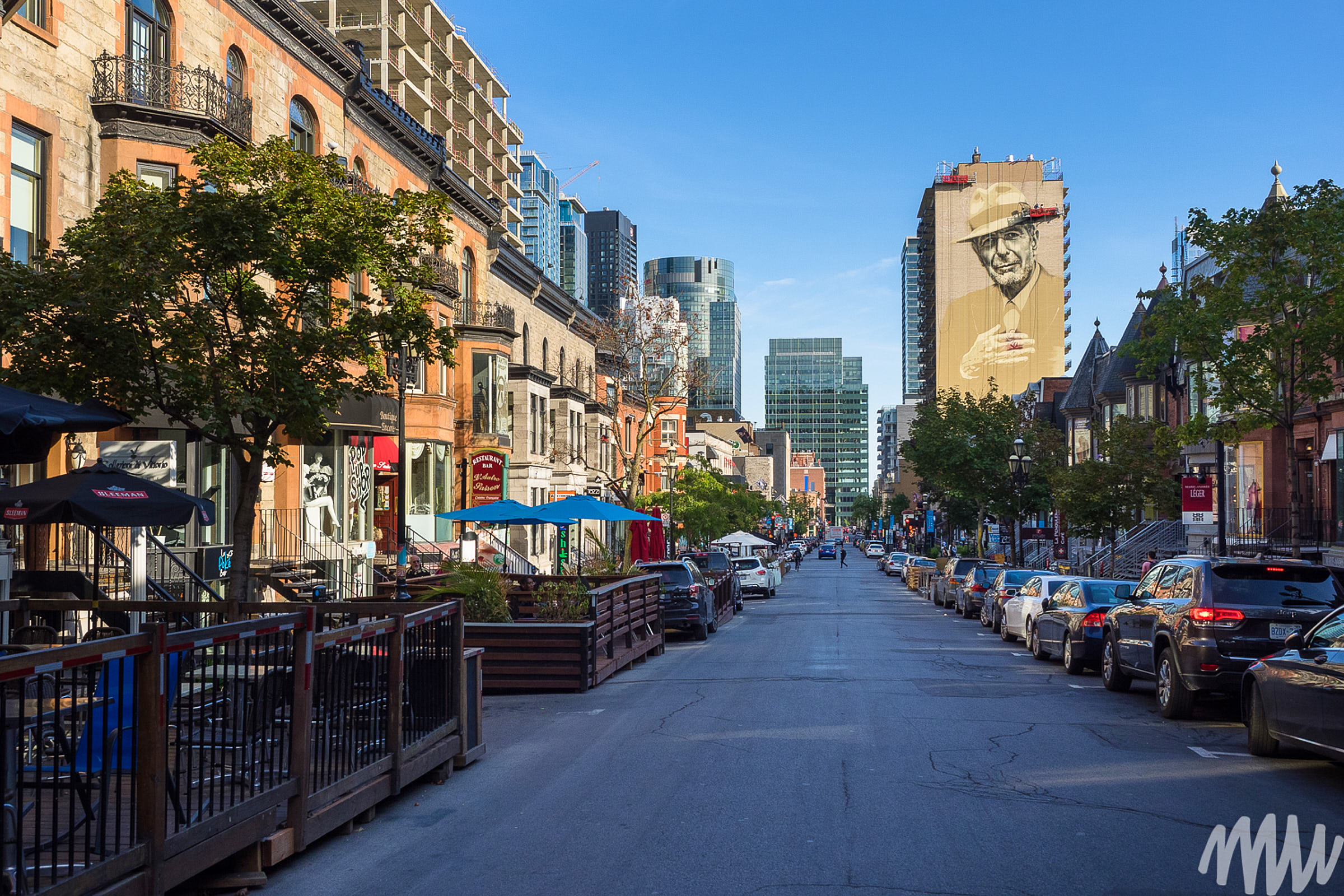 View of a street in Montreal and the mural of Leonard Cohen on a tall building 