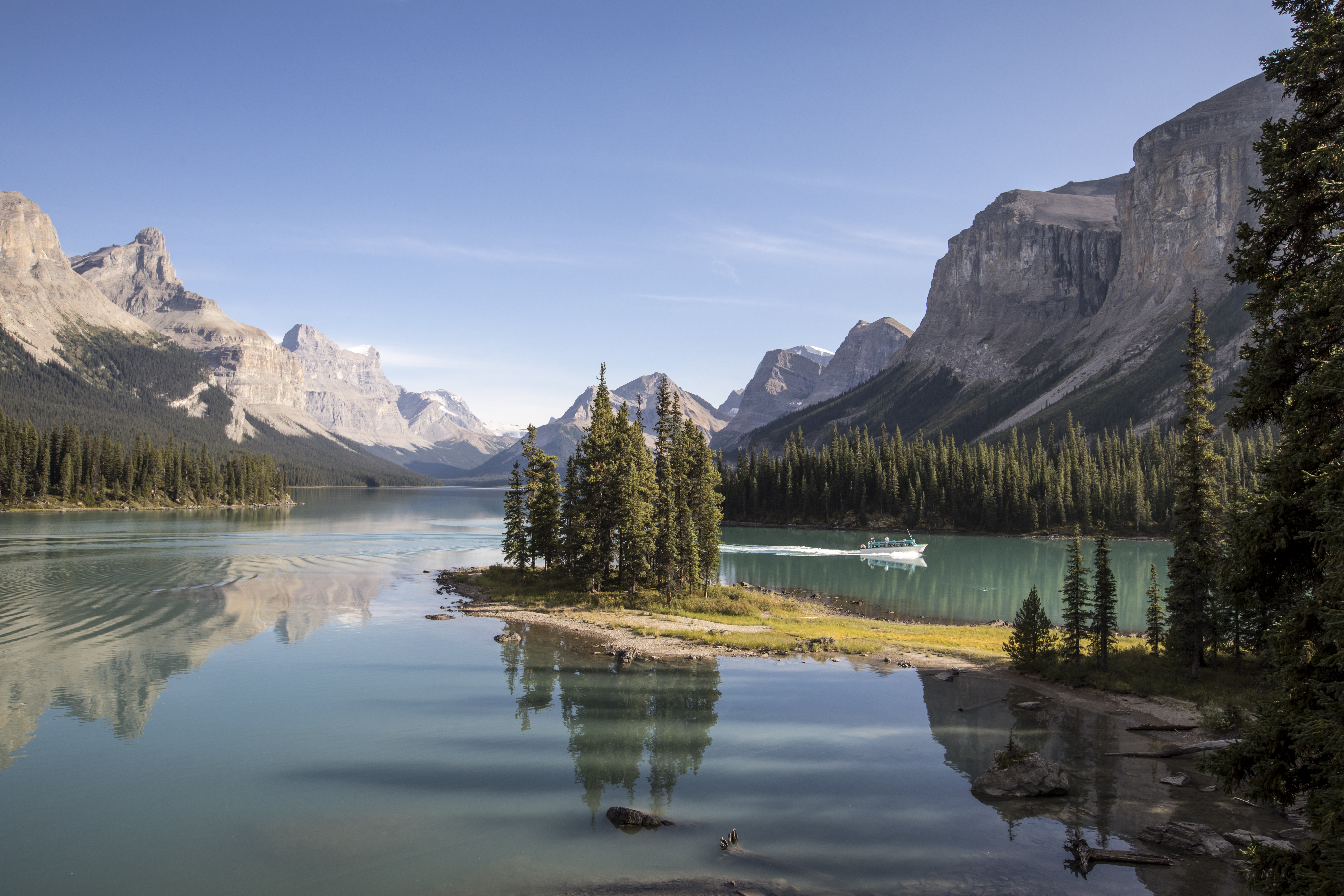 A small boat drives behind Spirit Island on Maligne Lake in the Rockies