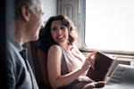 Couple smile and look at each other, sitting next to a window onboard a VIA Rail train