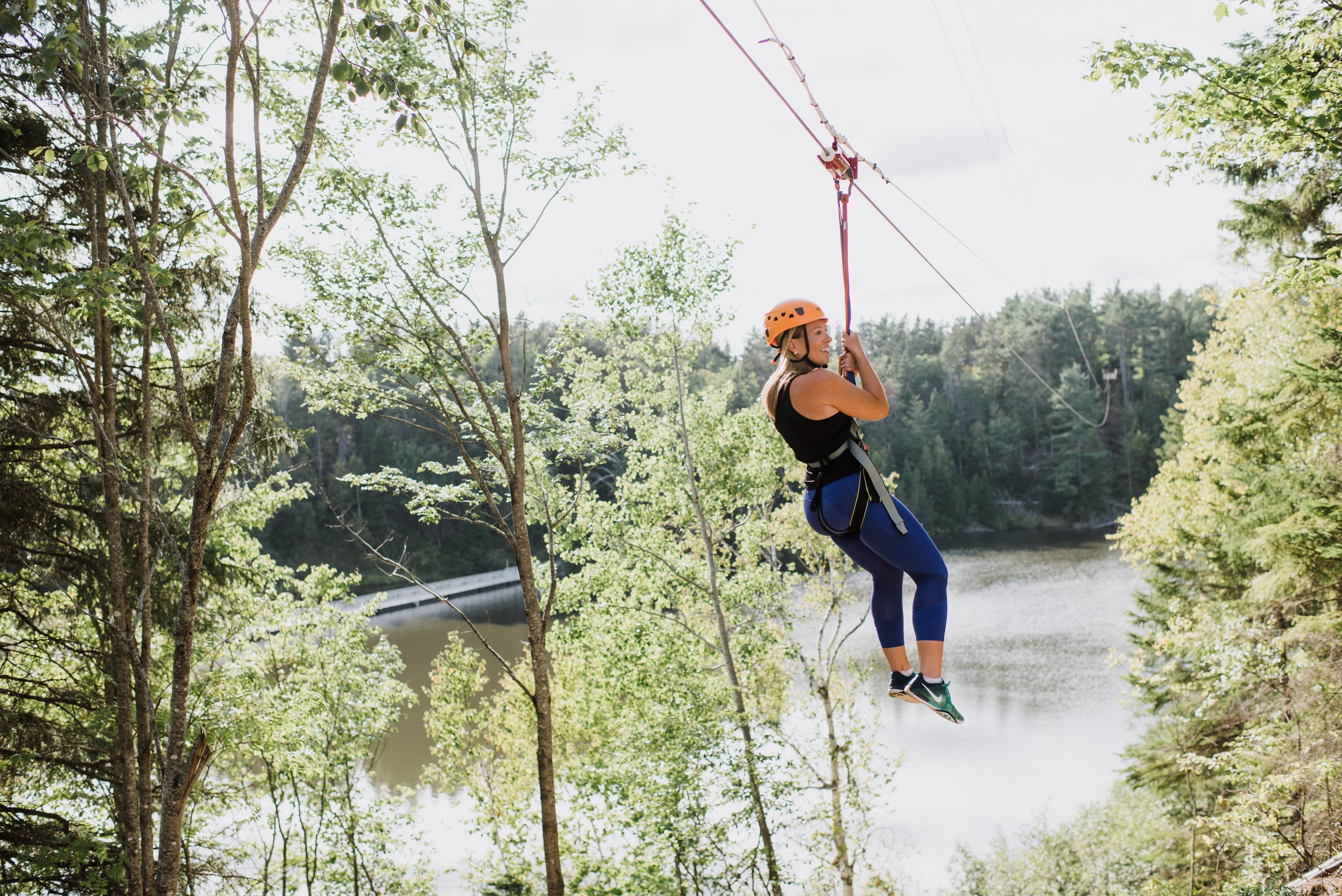Woman soars across park while ziplining in historical French Fort Cove Nature Park in Miramichi located in the Canadian Maritimes