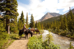 Group of people horseback riding by the river in the Tonquin Valley in Jasper National Park