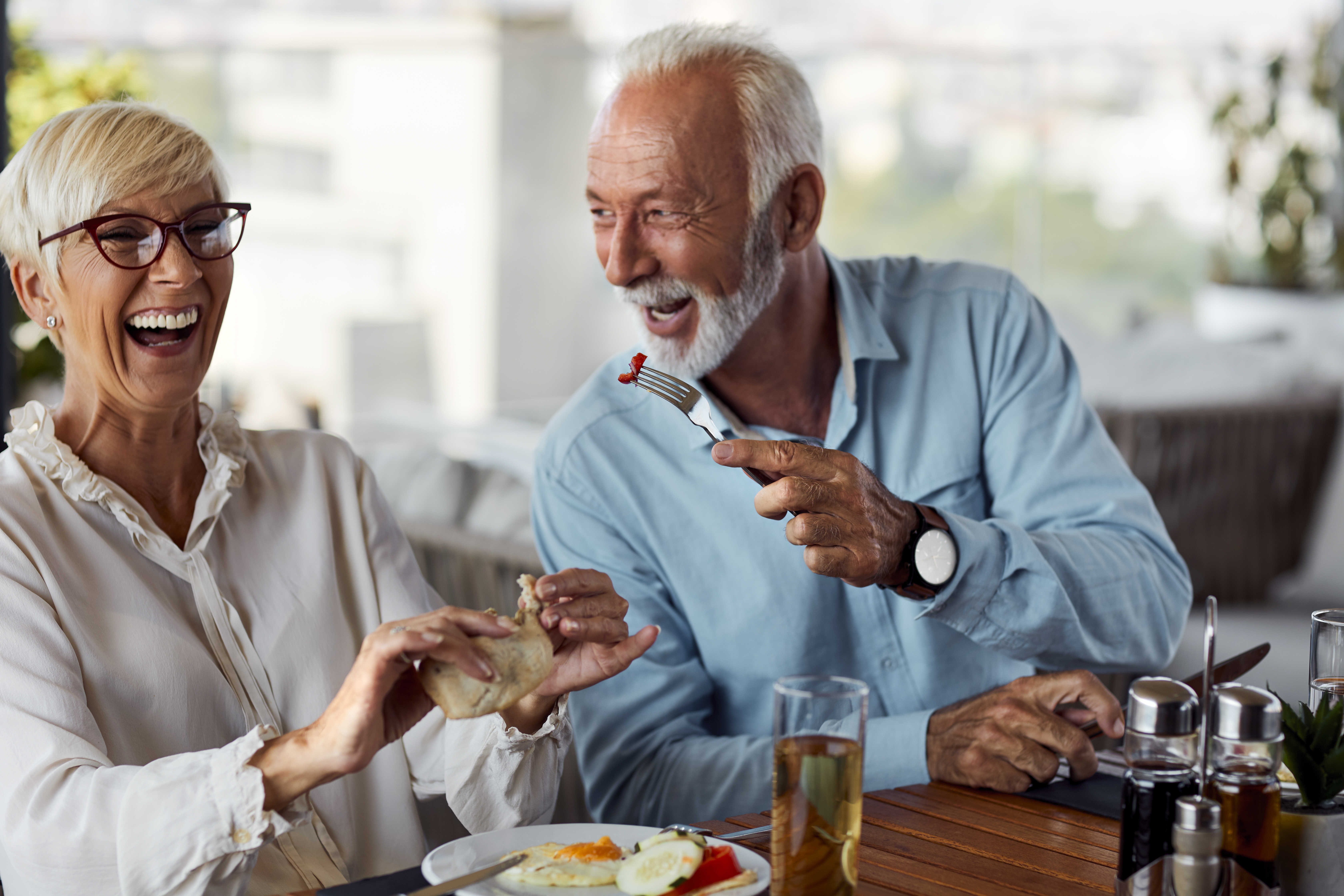 A senior couple laughing and having a hot breakfast in a restaurant