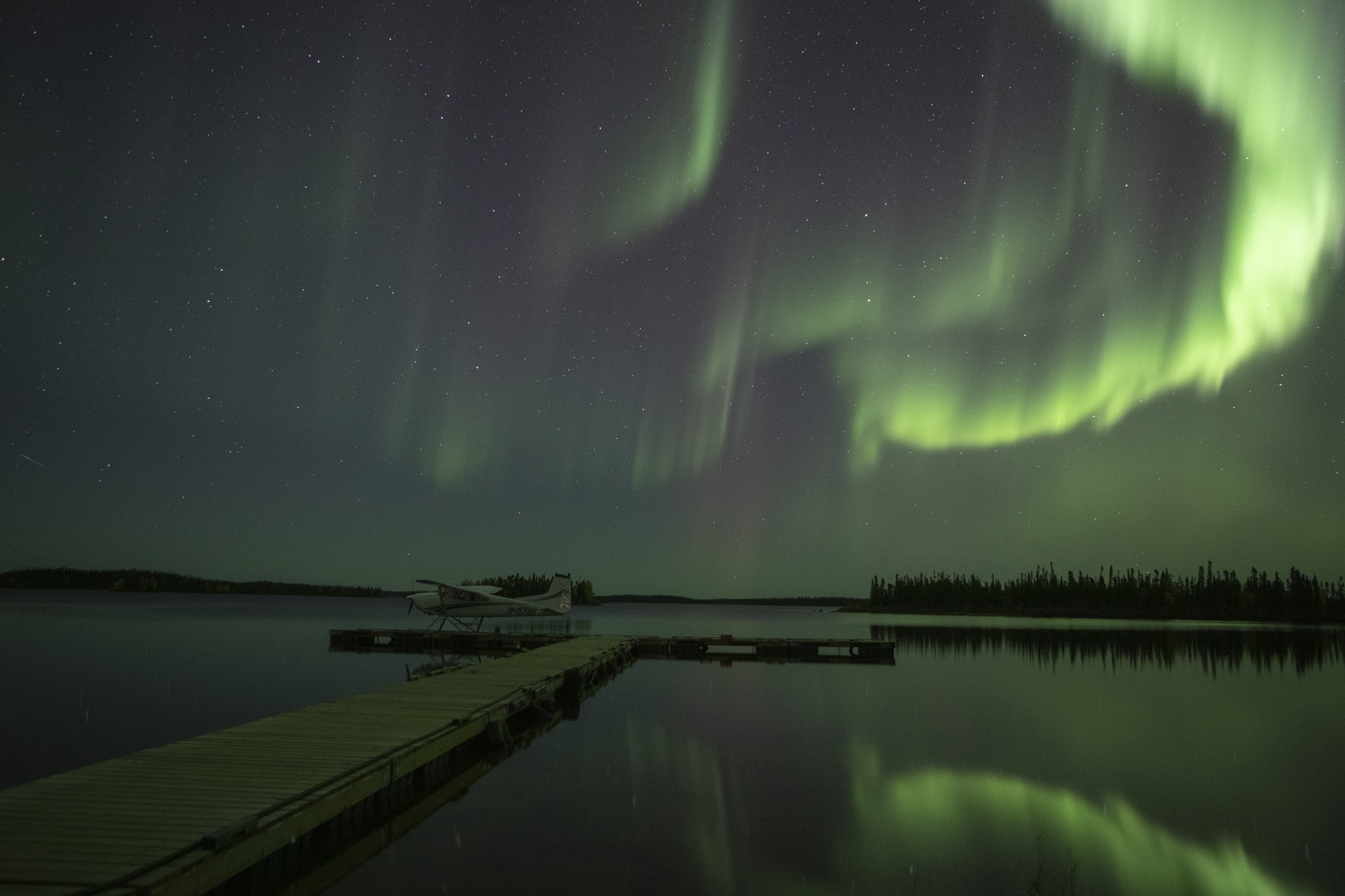 A photo showing the Northern Lights reflected in the water near the dock at Gangler's Subarctic Lodge