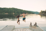 Couple jump off wooden dock into lake in Vancouver in the Summer