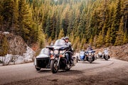 A group of motorcyclists with side cars riding through the Rockies