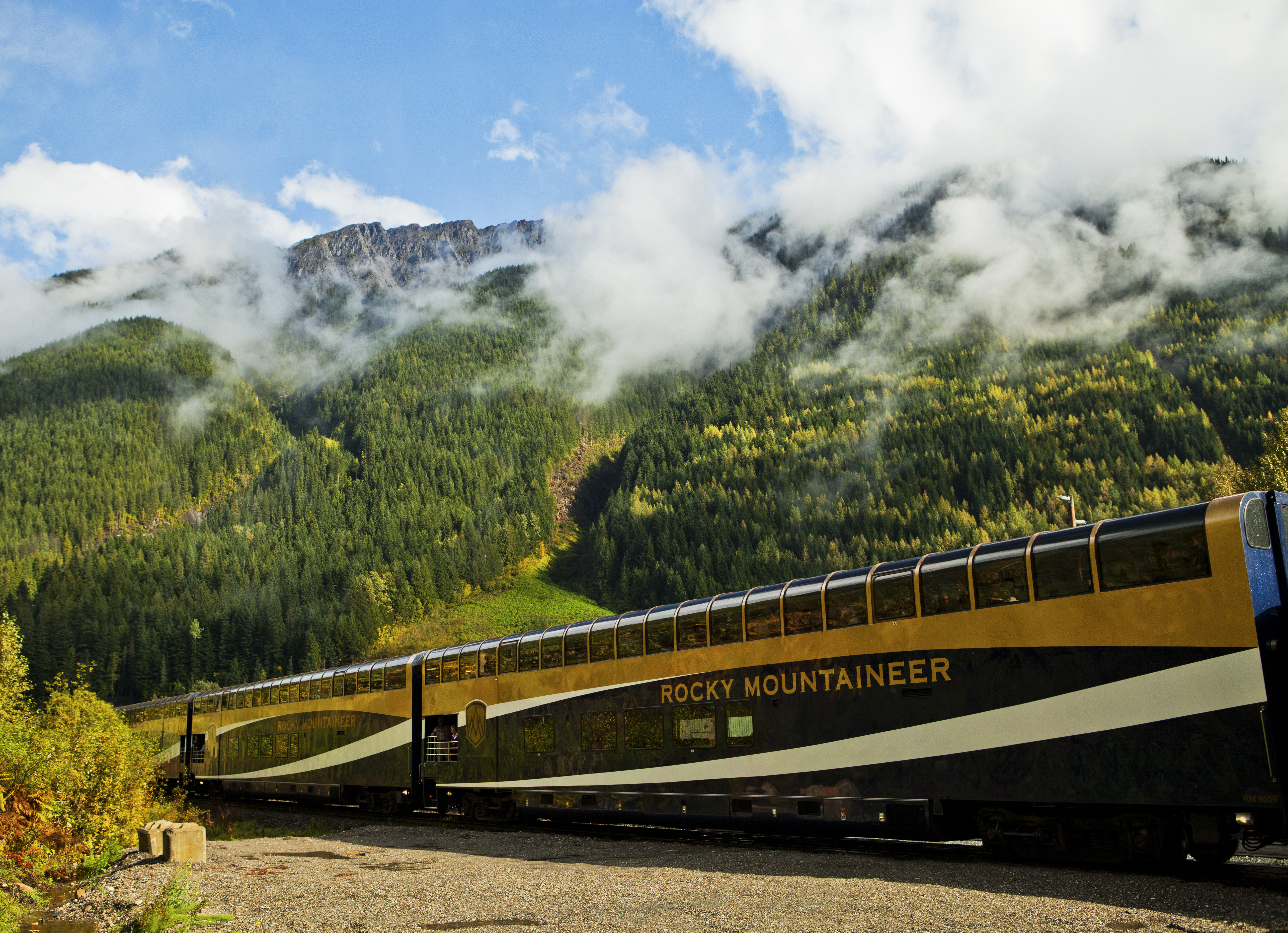 Rocky Mountaineer glass-domed train car passes lush valley