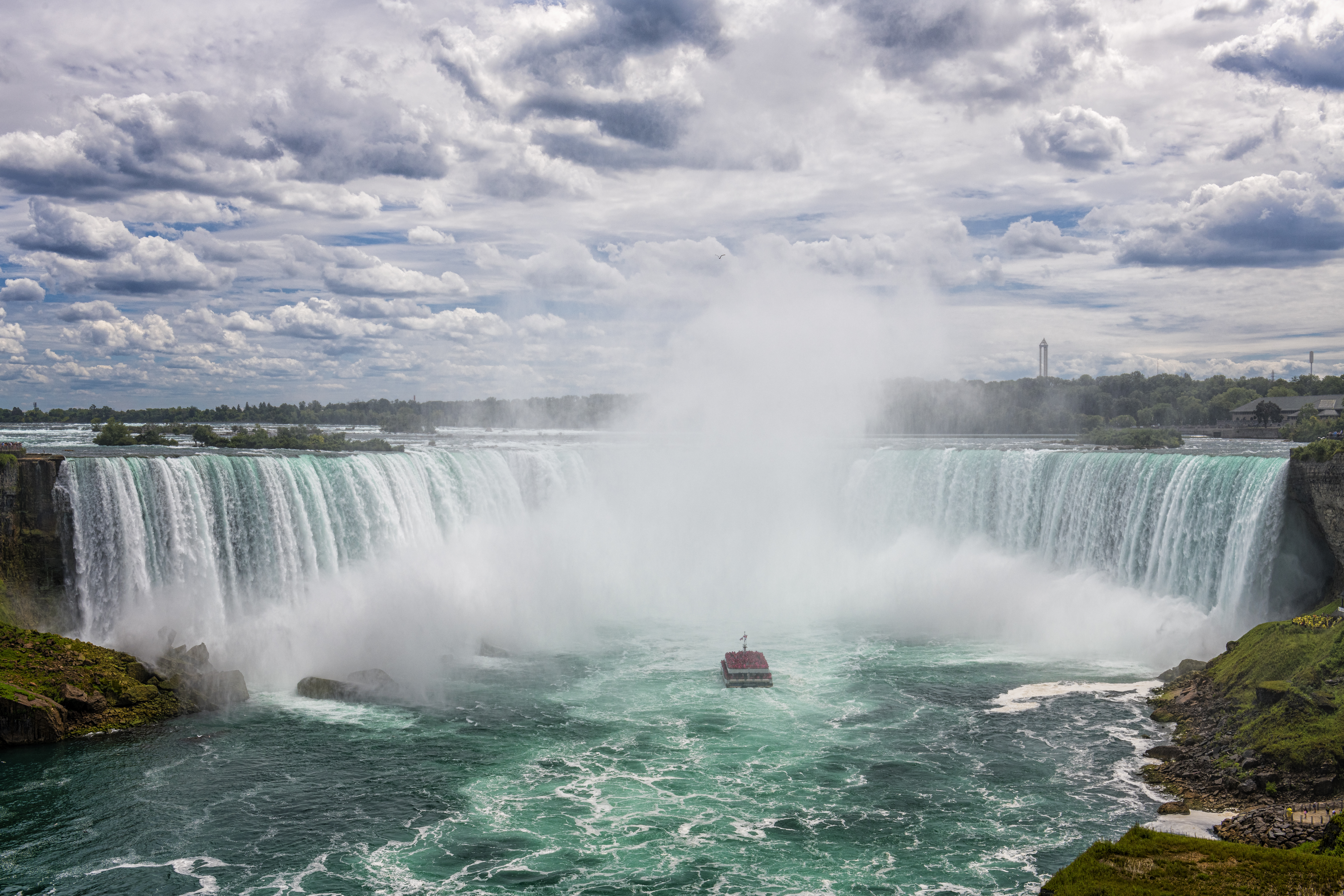 Boat cruise in Canadian Horseshoe Falls water roars down as mist sprays in Niagara Falls, Ontario