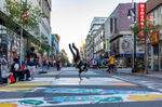 Dancer doing a one hand handstand on an art mural down Sainte-Catherine Street in Montreal