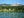 View of a blue lake in front of cabins at Southern Lakes Resort, with forest and mountains behind